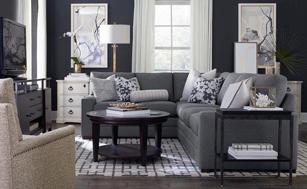 luxury living room featuring a grey couch with pillows, a black round table and light brown chair in a room with grey walls